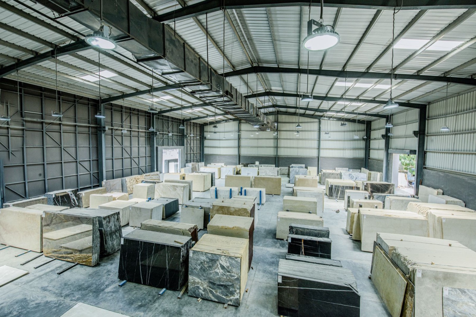 Blocks and slabs of marble stored in rows inside a stone warehouse